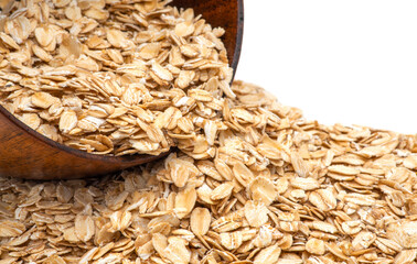 Oats spilling from wooden bowl with white background and copy space.