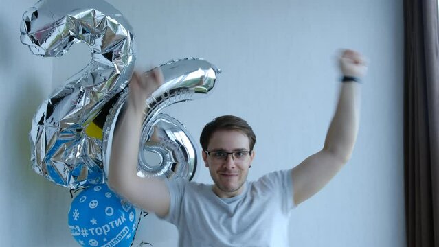 Caucasian man in glasses fun celebrating Happy birthday with ballons. Happy Birthday concept. 26 years old. Dancing and smile on a white background.