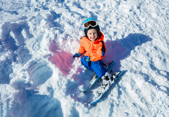 View from above of smiling little boy with ski and winter outfit