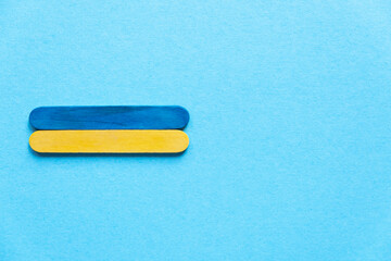 Ukrainian flag top view. Ukraine flag on a blue background, space for text. wooden sticks in the colors of the flag of ukraine on a blue background, top view. Ukraine's Independence Day. Wooden sticks