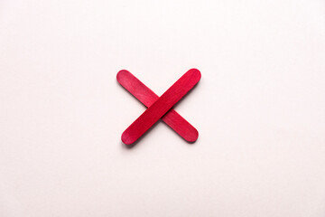 Obraz premium red cross made of wood on a beige background. prohibition sign