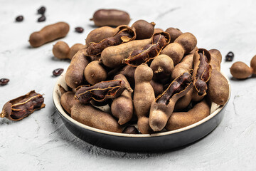 tamarinds beans in shell on a brown butchers block on a light background, healthy fruit. banner, menu, recipe place for text, top view