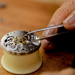 close up of a watch mechanisms and ruby with watchmaker repaiiring it