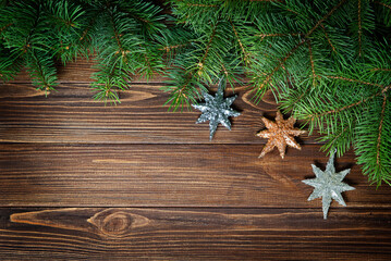 Christmas banner fir branches and three silver and gold stars on a wooden background.