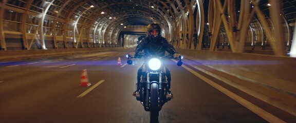 Biker riding his custom built cafe racer motorcycle through city at night. Shot with 2x anamorphic...