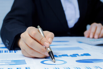 Businessman holding a profitability statistics analysis pen from a graph document in hand  to plan profit.