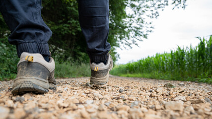 Low angle closeup view of male legs in hiking shoes walking on a country road