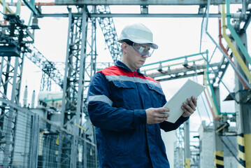An energy engineer inspects the modern equipment of an electrical substation before commissioning. Energy and industry. Scheduled repair of electrical equipment.