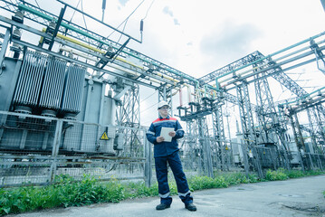 An energy engineer inspects the modern equipment of an electrical substation before commissioning....