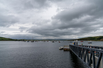 Fototapeta na wymiar the Rosmoney Pier and dock with many sailboats and yachts anchored in the waters of Clew Bay under an overcast sky