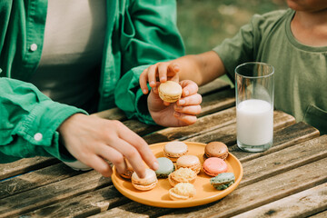 Little boy with a mother eats macaron cookies in outdoor