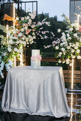 Beautiful wedding cake covered in chocolate velour with gradient and fresh flowers. Beautiful pink hydrangea. Outdoor registration area with a backdrop of a lake and green trees. 