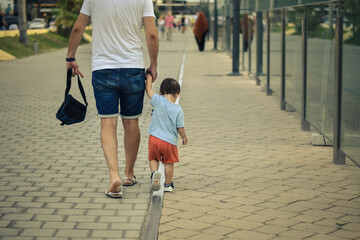 Padre e hijo caminando por la calle cogidos de la mano de espaldas
