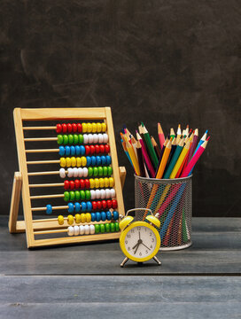 Back to school. Colorful pencils, math Abacus and alarm clock on blue desk