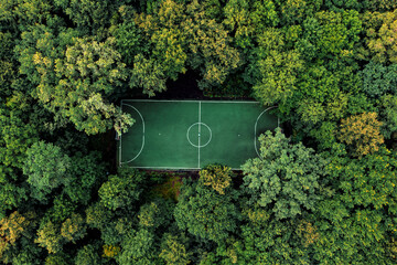 Drone top down view of beautiful shcool football field in summer deciduous forest. Calm cloudy day...