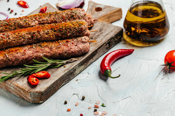 raw Lula kebab on skewers with spices on a cutting board light background. Lula kebab, traditional Caucasian dish. Long banner format. top view
