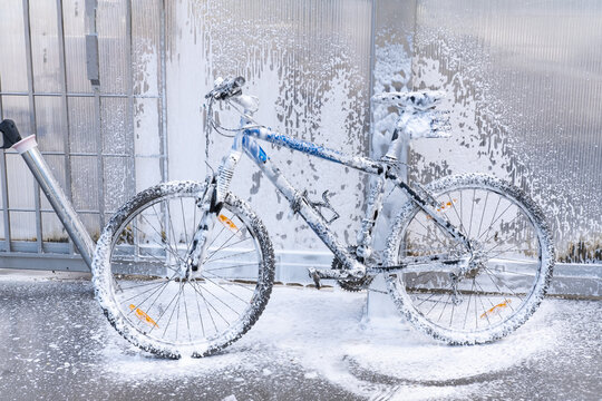 Washing a bicycle with a foam jet at a car wash. The bike is covered with foam. Self-service. Bicycle maintenance