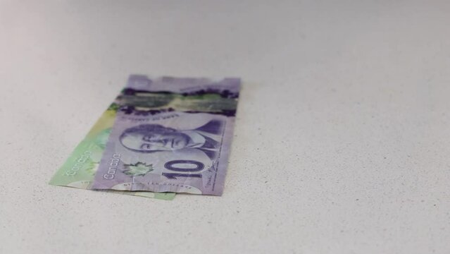 Counting Out Canadian Dollars on a White Counter