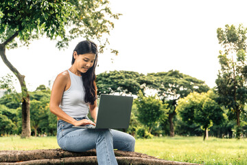 Happy smiling woman using a laptop in a park