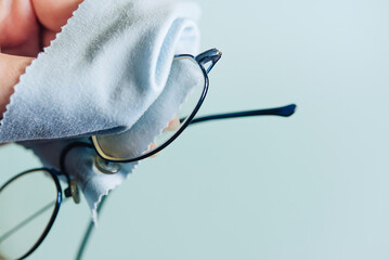 hand wipes glasses with a napkin on a blue background. Glass cleaning cloth, napkin