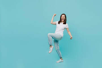 Fototapeta na wymiar Full body side view young woman 20s she wear white t-shirt doing winner gesture celebrate clenching fists say yes isolated on plain pastel light blue cyan background studio. People lifestyle concept.
