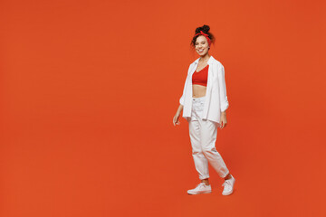 Fototapeta na wymiar Full body young cheerful happy fun cool woman of African American ethnicity 20s wearing white shirt top walking going look camera isolated on plain orange background studio. People lifestyle concept.