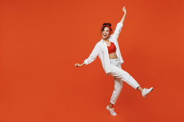 Full body side view young smiling happy cheerful cool woman of African American ethnicity wear white shirt top dance raise up hands legs isolated on plain orange background. People lifestyle concept. - obrazy, fototapety, plakaty