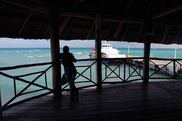 Silhouette of a man at the maritime station watching Ferries moored ready to depart in Playa del Carmen, Mexico