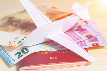 Passport with Euro banknotes and a paper airplane in origami style.