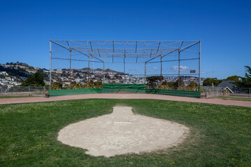 Pitcher's mound view of empty community baseball field against blue sky.