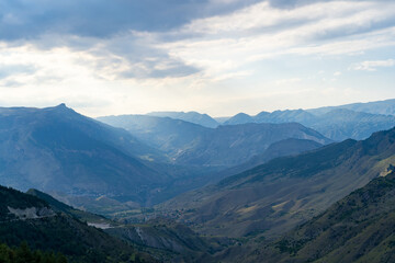 Amazing landscape of mountain range with sunset sky and clouds and rural village in mountain valley in Dagestan. Scenery of mountain layer at dusk.