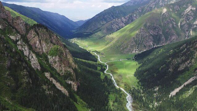 Altyn-Arashan Valley in Issyk Kul Region in Kyrgyzstan. Drone footage 4K. Slow epic motion. Green fields in valley and forest, mountains around.