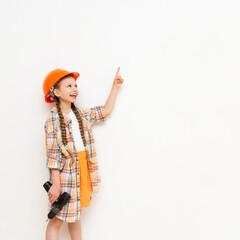 A little girl with a drill in her hands to show your advertisement on a white isolated background. The concept of renovation in the children's room. Copy space.