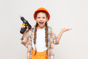 A little girl with a drill in her hand holds your advertisement on a white isolated background in the palm of her hand. The concept of renovation in the children's room.