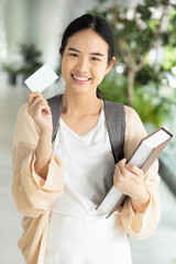 Happy smiling Asian female student holding blank credit card, concept of student card, student...