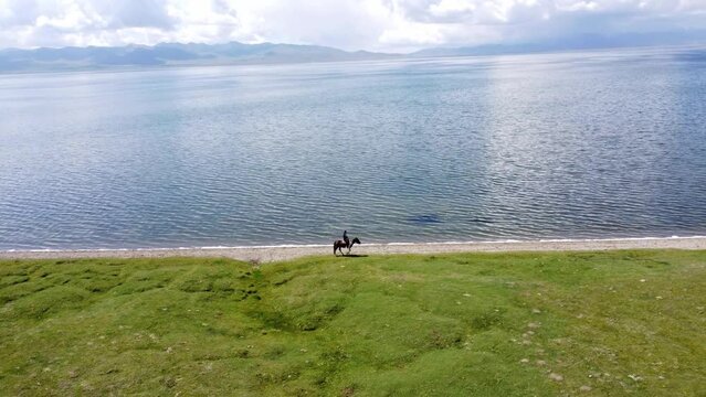 Mans ride on horses near to Song-Kul lake in Kyrgyzstan. Drone footage 4K.