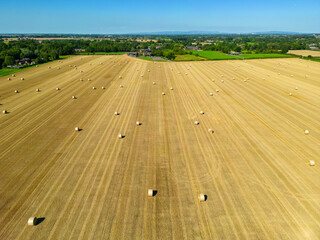 High level aspect view over a wheat field with bales of straw ready for collection in the English...