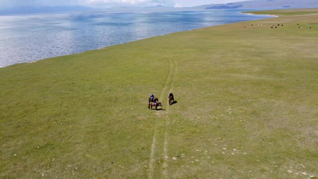 Mans ride on horses near to Song-Kul lake in Kyrgyzstan. Drone footage 4K.