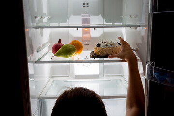 Woman reaching hand for cake, the choice between healthy and harmful food