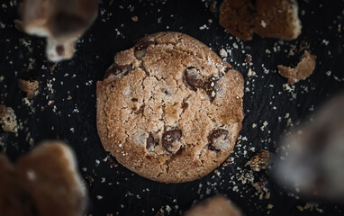 Round cookies on a black background with crumbs and pieces of cookies floating in the air.