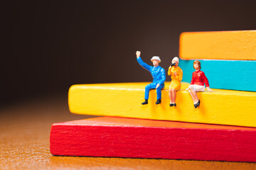 Miniature people, man and woman sitting on colorful wooden using as business and social concept