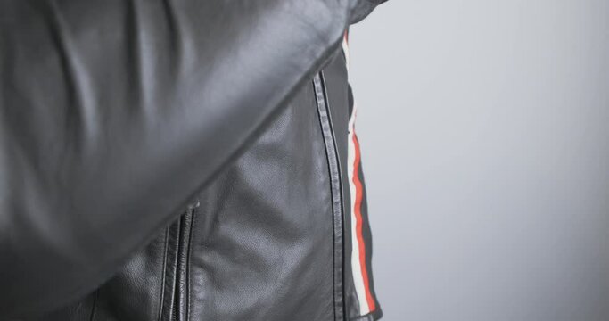 Motorcyclist unzip black moto jacket. Close-up, side view of the chest, indoors. Concept of protection when riding a motorcycle, preparing for a trip.