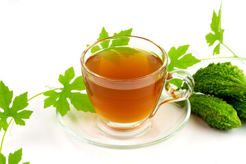 Bitter gourd or bitter melon tea in transparent cup and fresh bitter gourd with green leaf isolated...