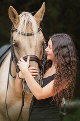Equestrian and her horse team: Portrait of a young woman cuddle with her palomino kinsky warmblood...