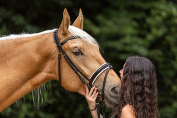 Portrait of a young woman cuddle with her palomino kinsky horse in summer outdoors - obrazy, fototapety, plakaty