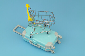 Travel and shopping concept. Shopping cart on travel suitcase close-up.