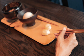 Fototapeta na wymiar Close up of hand of woman eating asian food with chop sticks
