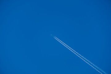 Airplane contrail against clear blue sky background with copyspace.