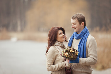 couple on a date walk in autumn or winter park. Valentine's Day for couple in rustic style. Happy couple in love. Casual outfit with Blue accessories: scarfs and mittens. Cozy winter in Pine forest