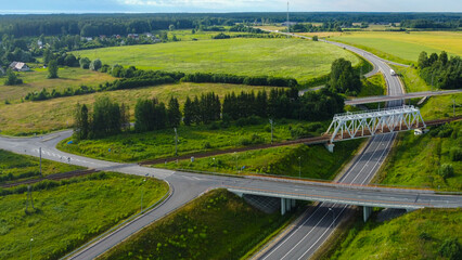 Aerial view of an automobile road junction intersection with bridges and trucks and cars on a sunny day against a green lawn